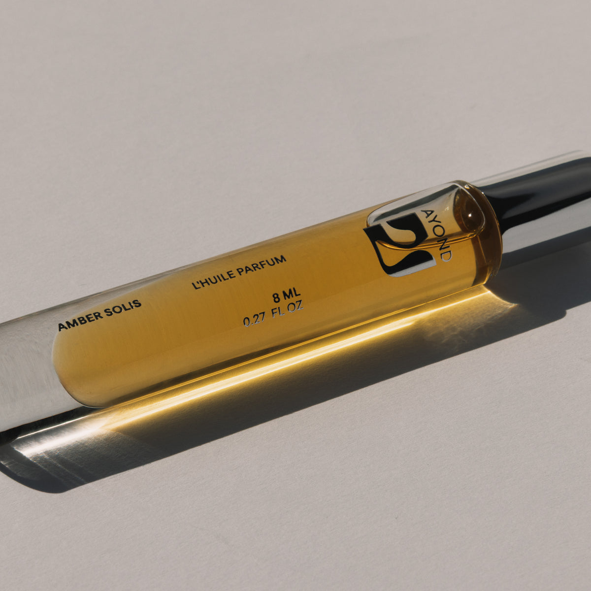 Amber Solis Perfume Oil rollerball resting on glass