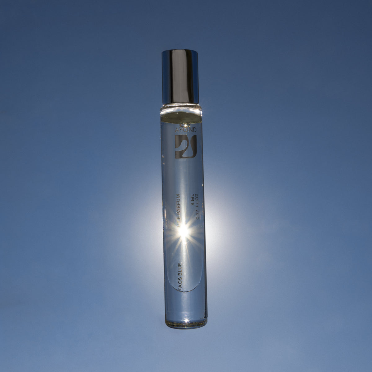 Taos Blue Perfume Oil held up against the sun and blue sky