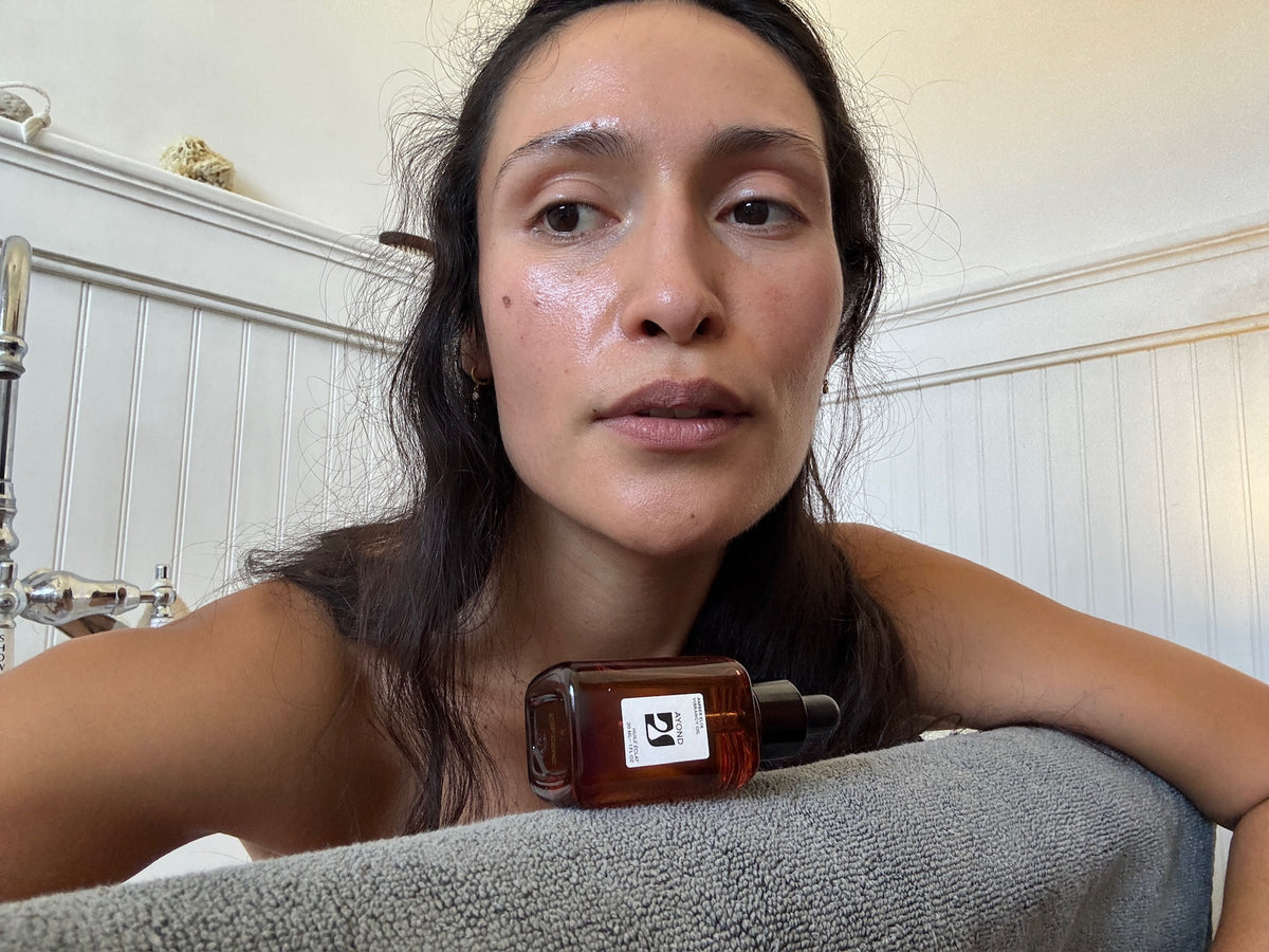 Woman holding an AYOND bottle while resting on a pillow