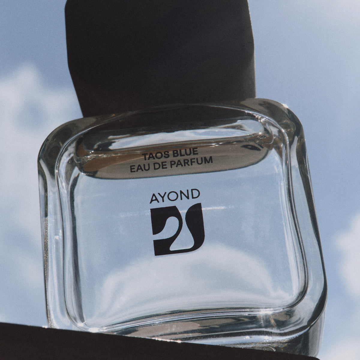 Taos Blue Eau de Parfum bottle against a blue sky