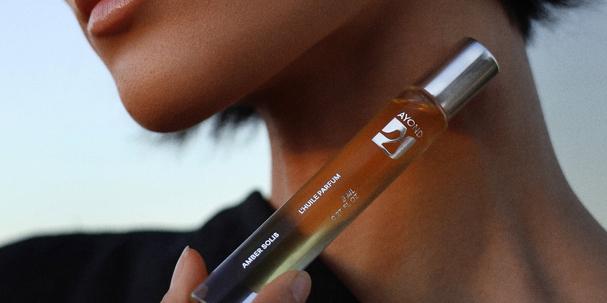 Woman holding Amber Solis Perfume Oil to her neck