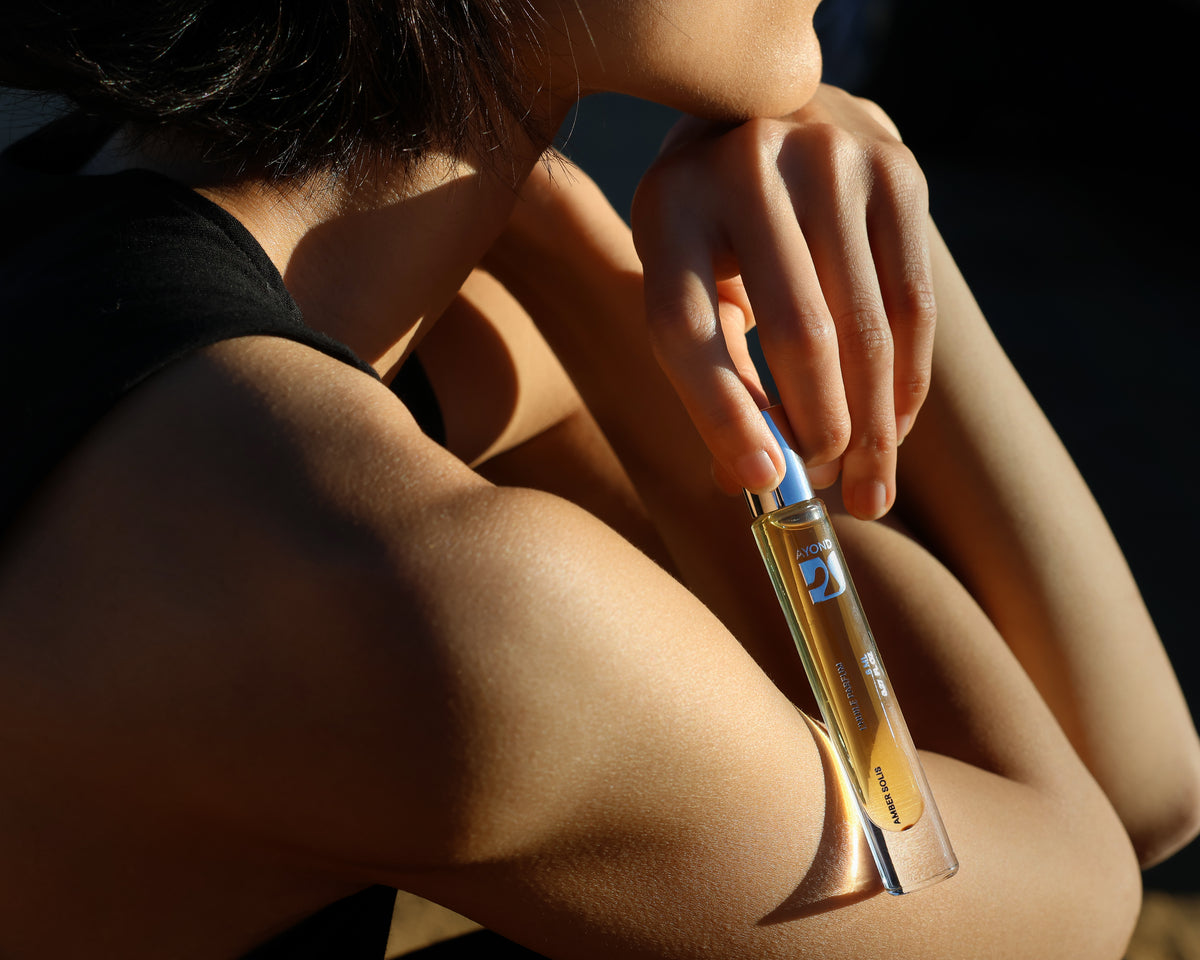 Woman applying an AYOND perfume oil rollerball to her wrist