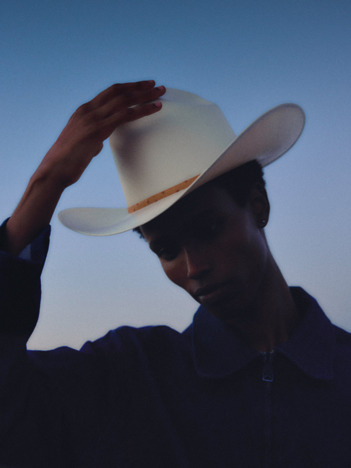 Silhouette of a person in a cowboy hat against a blue sky