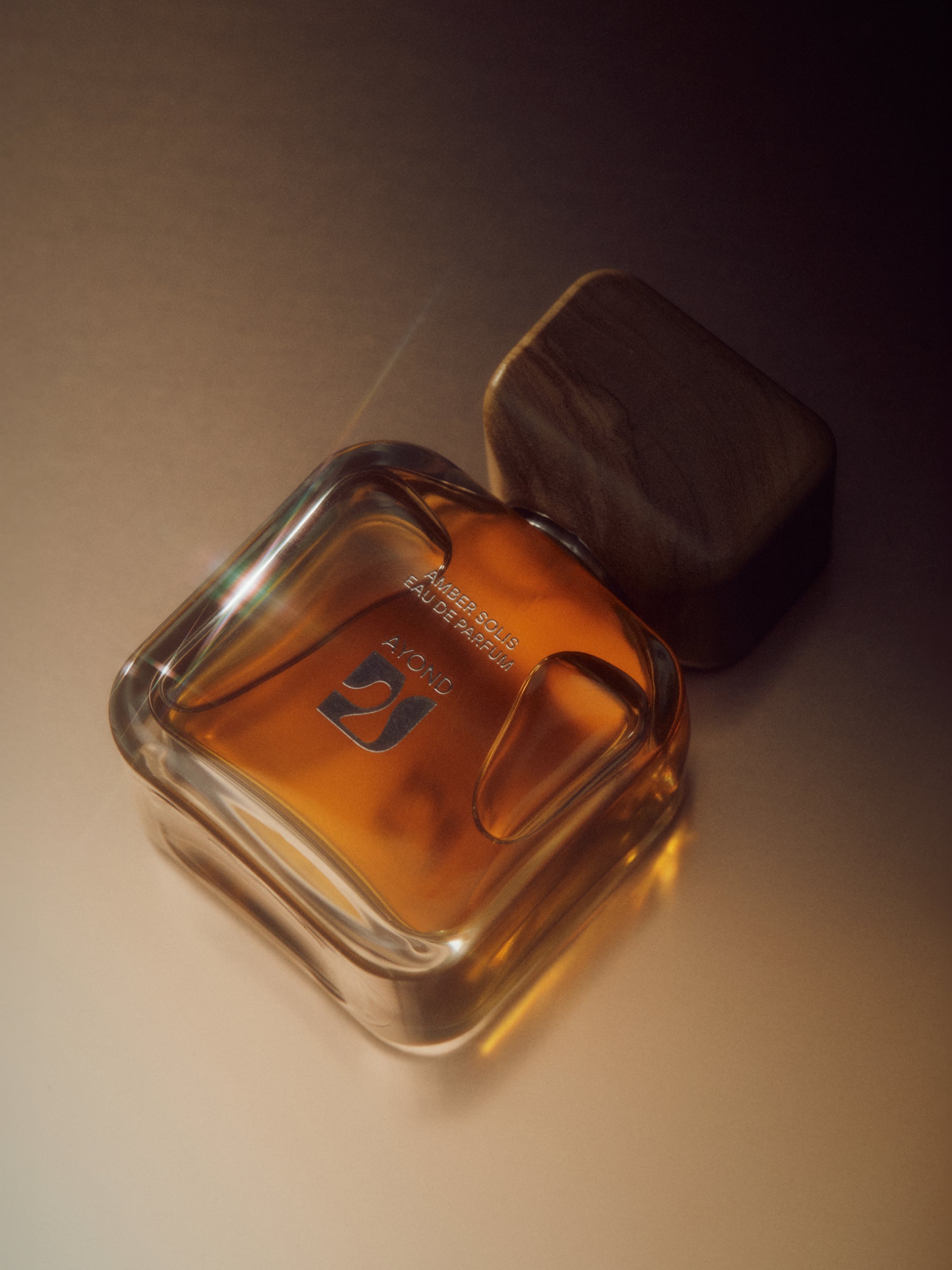 Amber Solis Eau de Parfum bottle in warm golden light