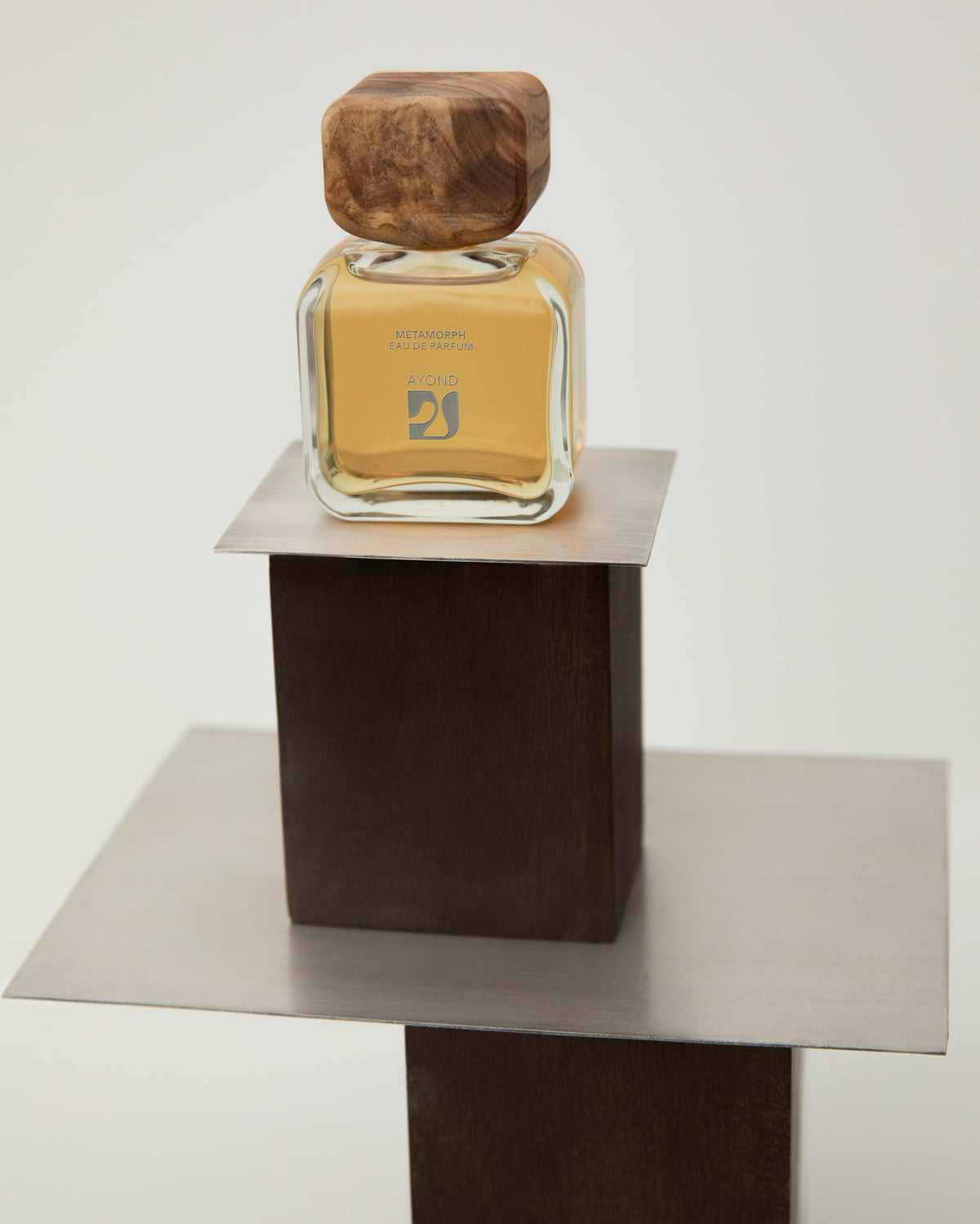 AYOND eau de parfum bottle on a wooden pedestal