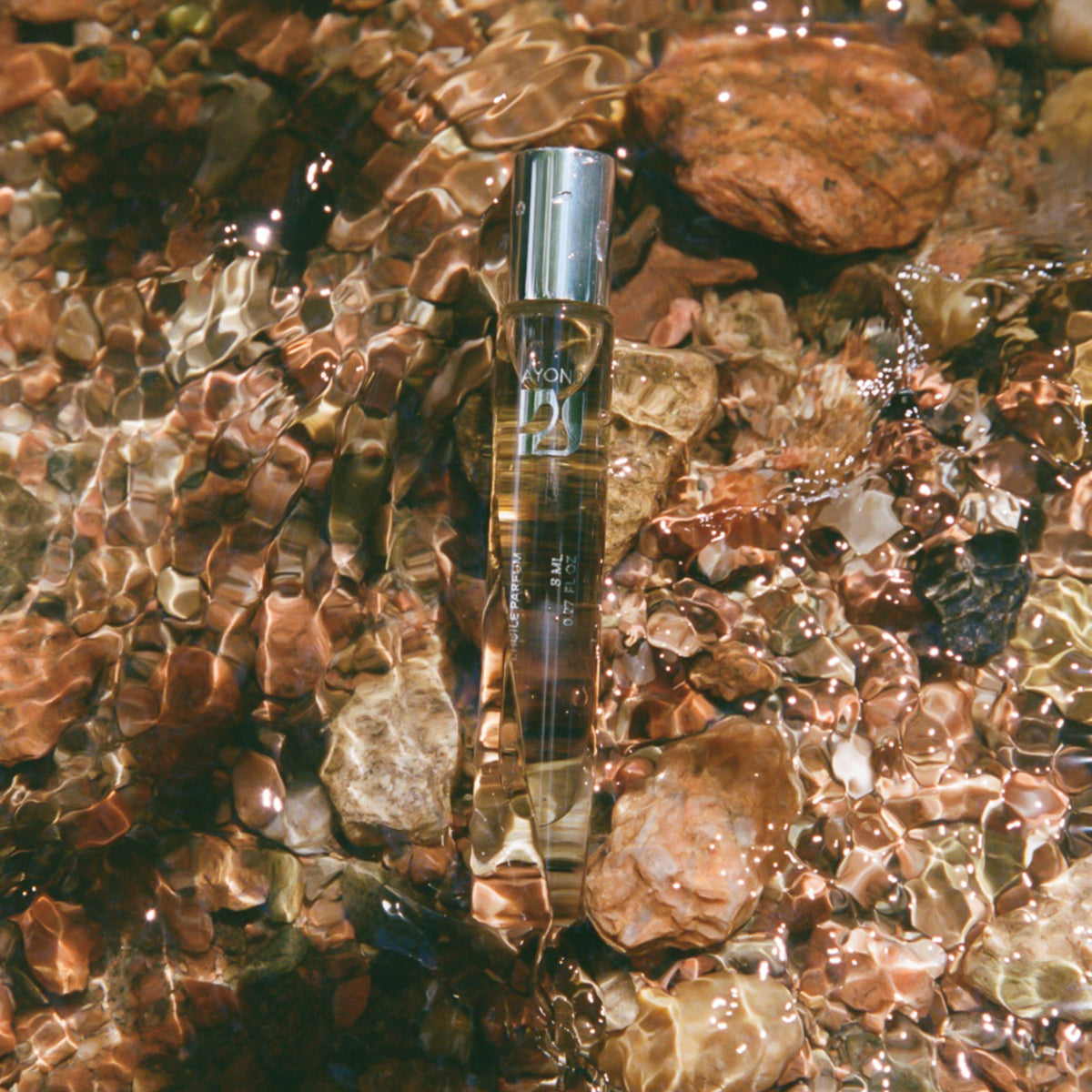 Metamorph Perfume Oil rollerball among dried botanicals and wood shavings