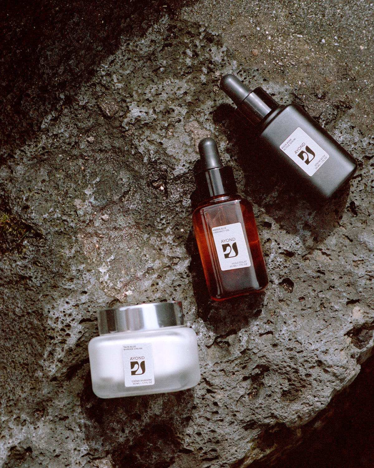 AYOND skincare bottles and jar arranged on a rock