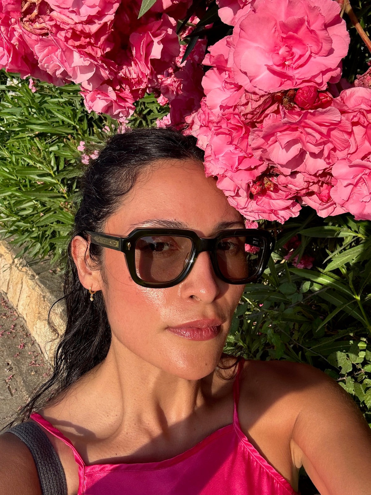 Woman in sunglasses in front of pink flowers